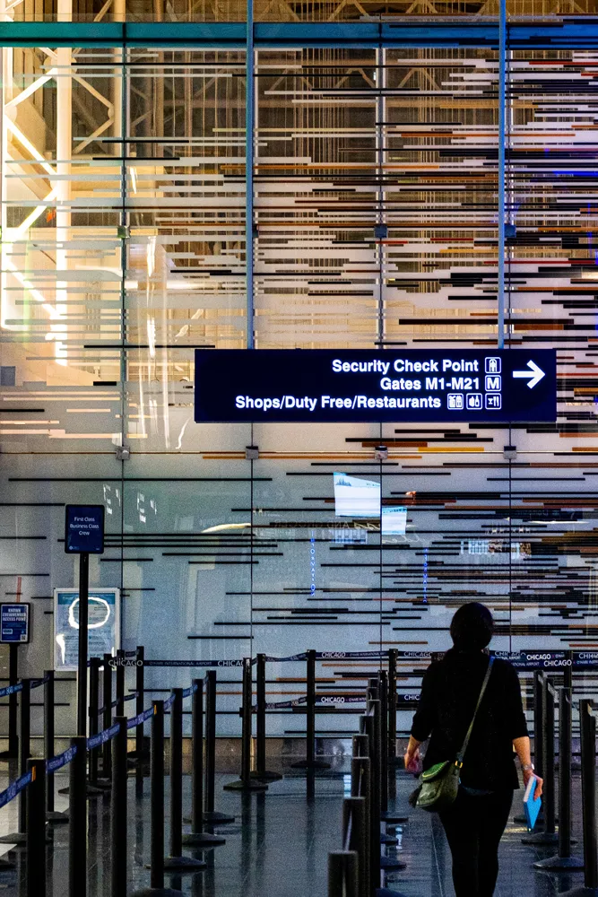 A traveler approaches an airport security checkpoint under directional signage.