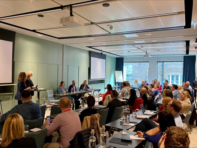 A professional panel discussion in a modern conference room with an engaged audience.