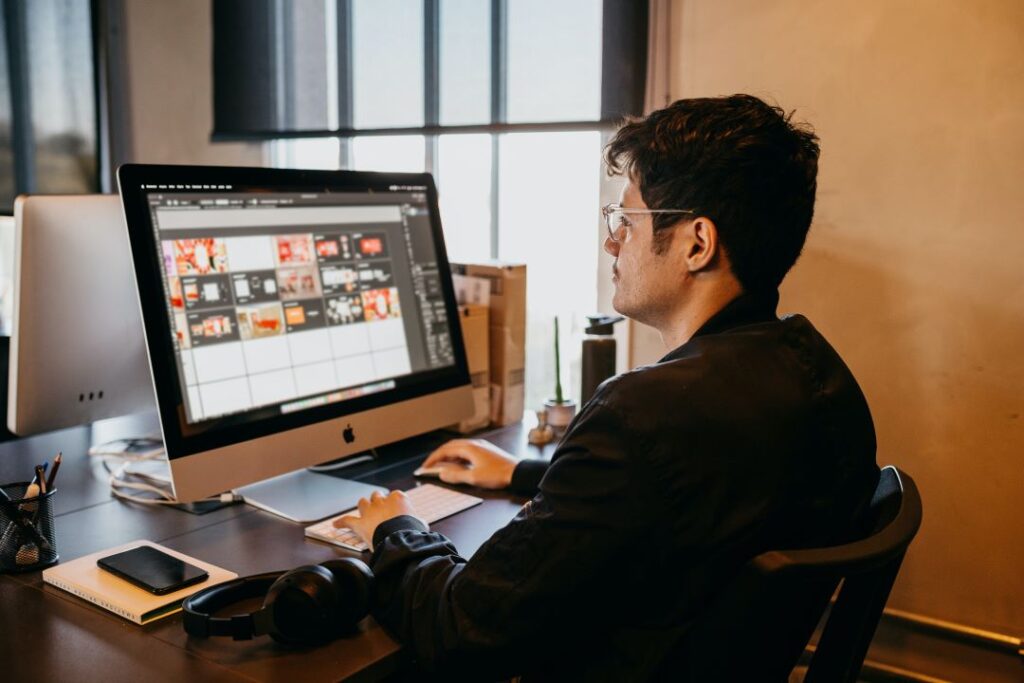 A person works on a desktop computer in a modern office, editing visuals on a design software.