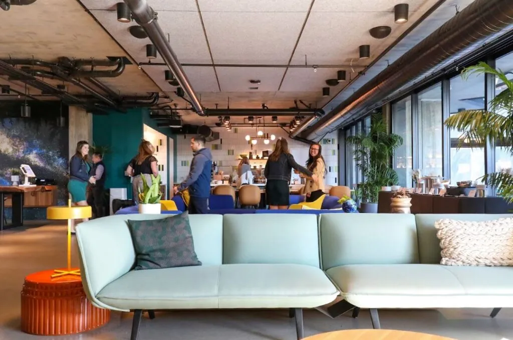 A modern, open-concept lounge with stylish furniture, vibrant decor, and people interacting casually.