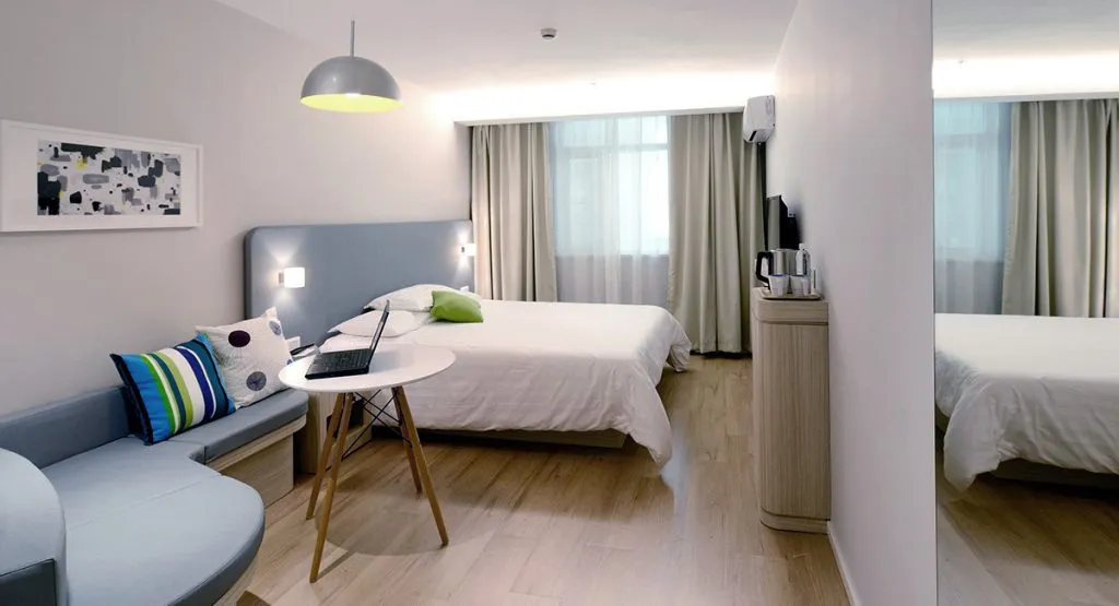 Modern hotel room with minimalist decor, featuring a bed, seating area, and natural lighting.