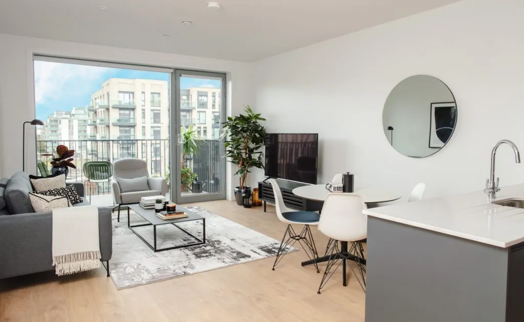 Modern open-plan living space with sleek furniture, large windows, and a balcony view.