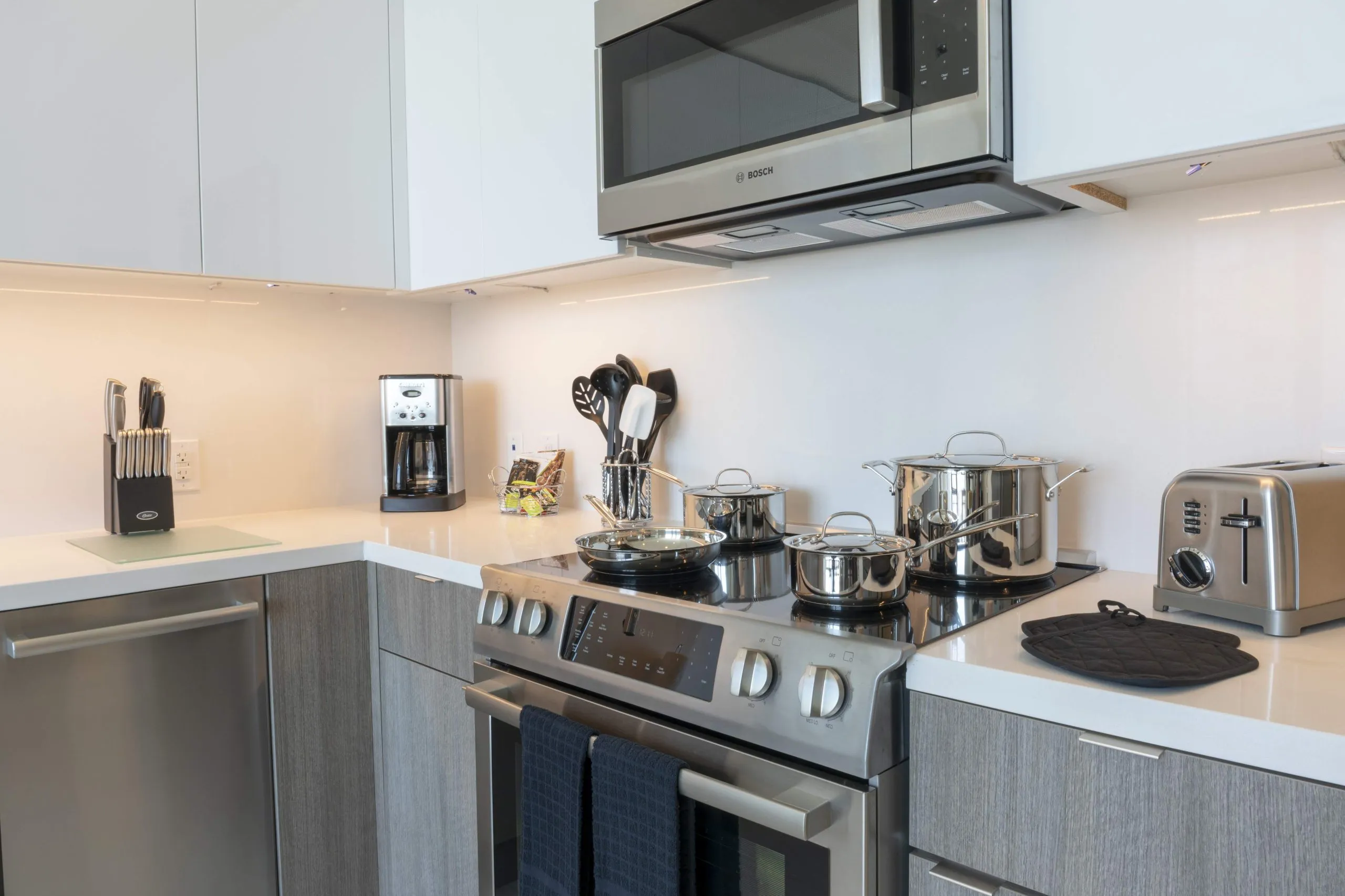 Modern kitchen with stainless steel appliances, cookware, and sleek cabinetry.
