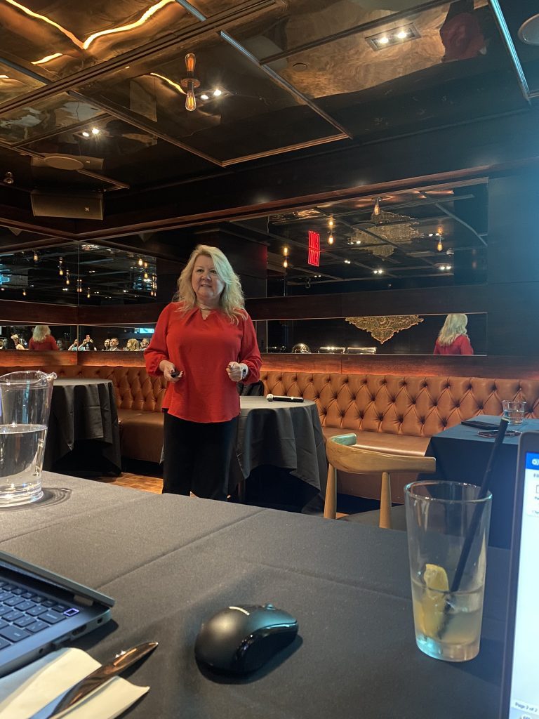 A woman in a red top stands in a modern, dimly lit restaurant with mirrored ceilings.