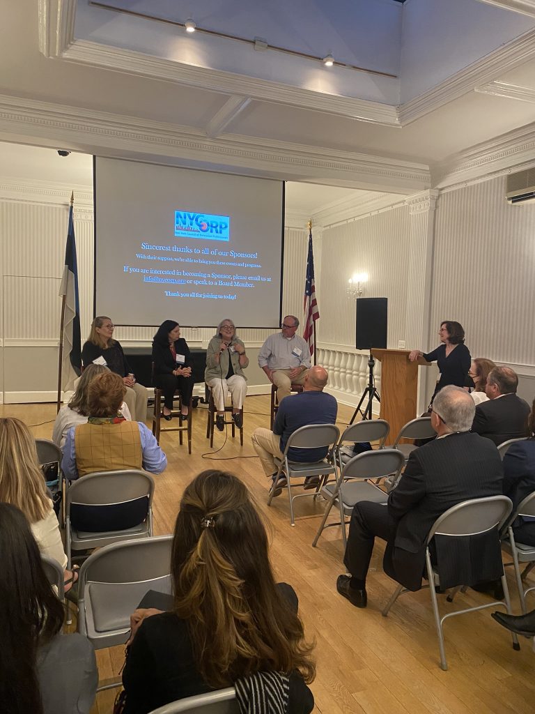 Panel discussion in a formal setting with audience seated, featuring NYCRP sponsor acknowledgment.