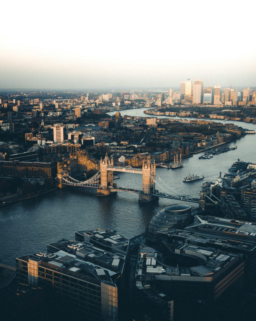 Aerial view of London's Tower Bridge spanning the Thames, with Canary Wharf in the background.