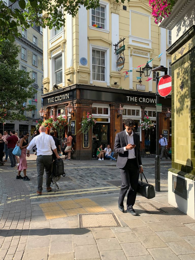 The Crown pub stands on a sunny street corner, surrounded by pedestrians and vibrant decorations.