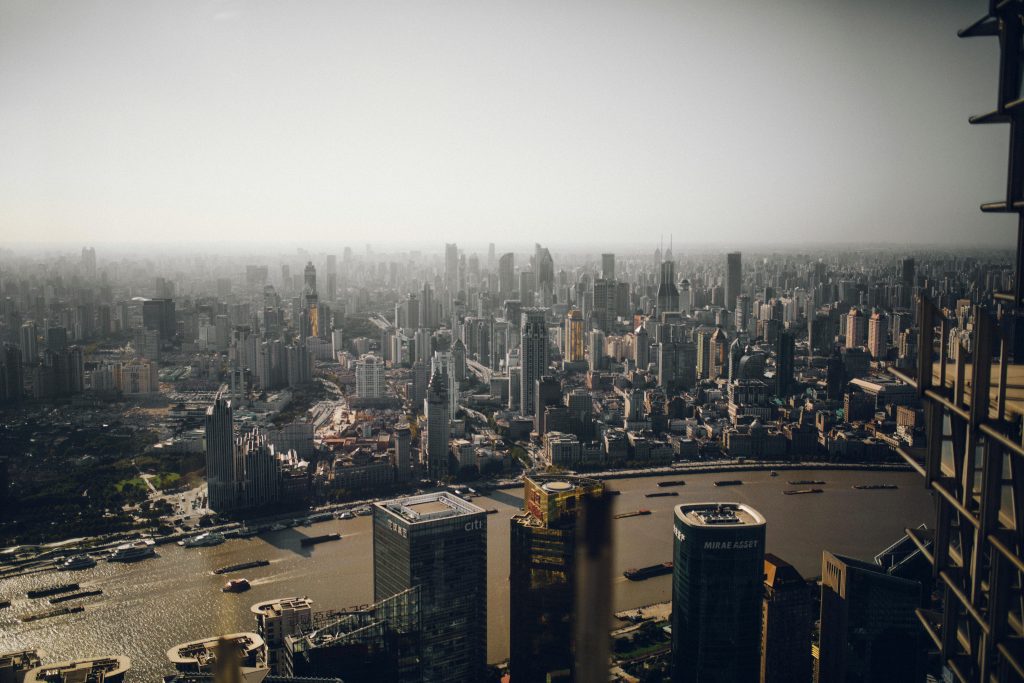 A sprawling urban skyline with dense skyscrapers and a river cutting through the cityscape.