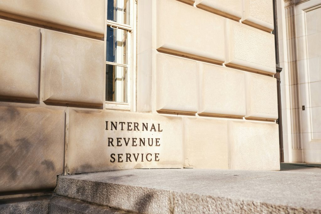 The IRS building exterior features beige stone walls with its name engraved near a window.