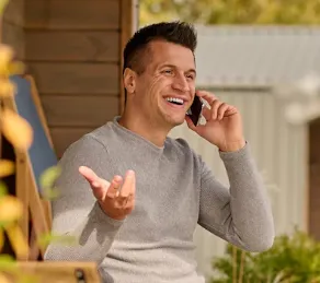 A man sitting in a chair talking on a cell phone.
