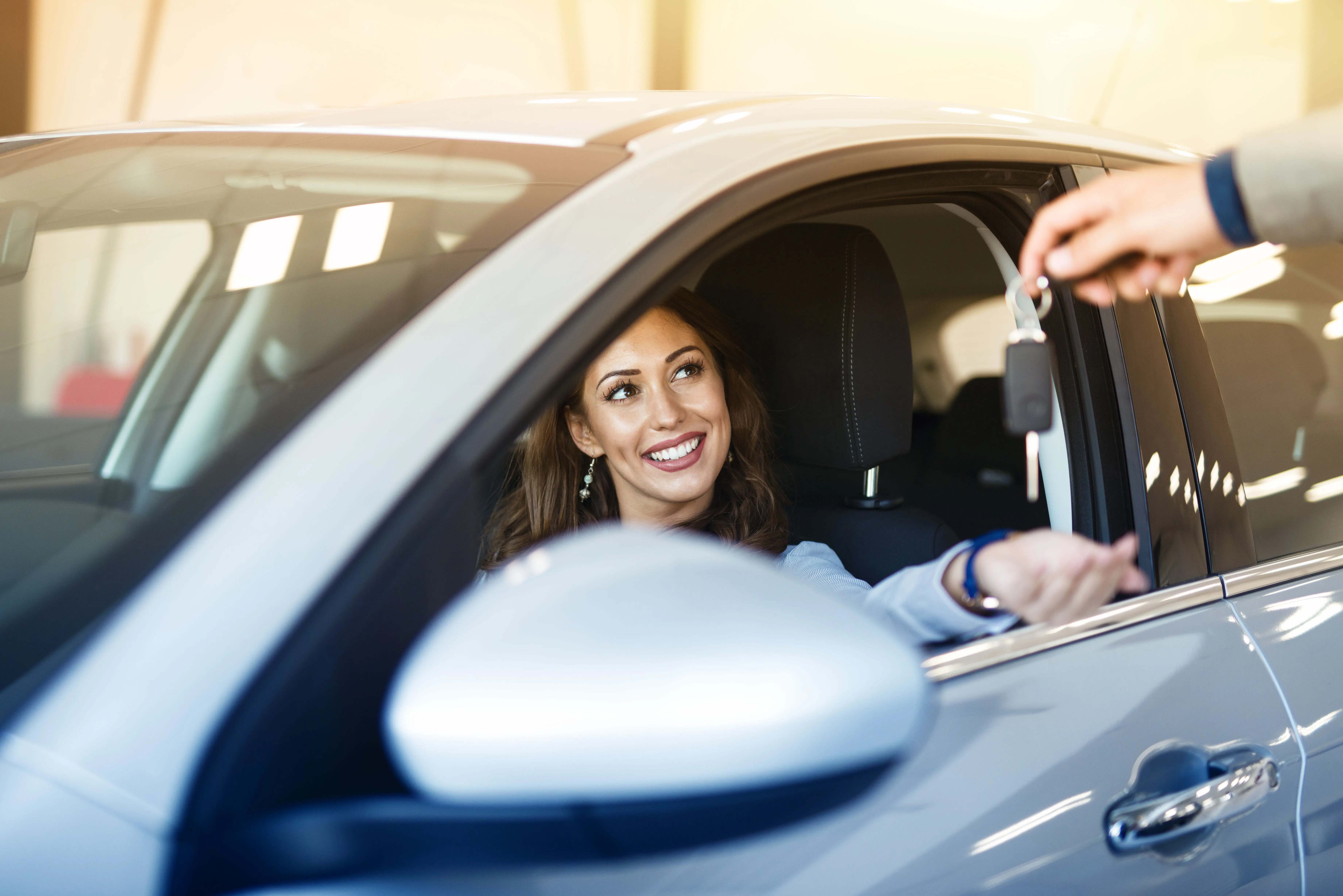 A woman sitting in a car holding a car key.
