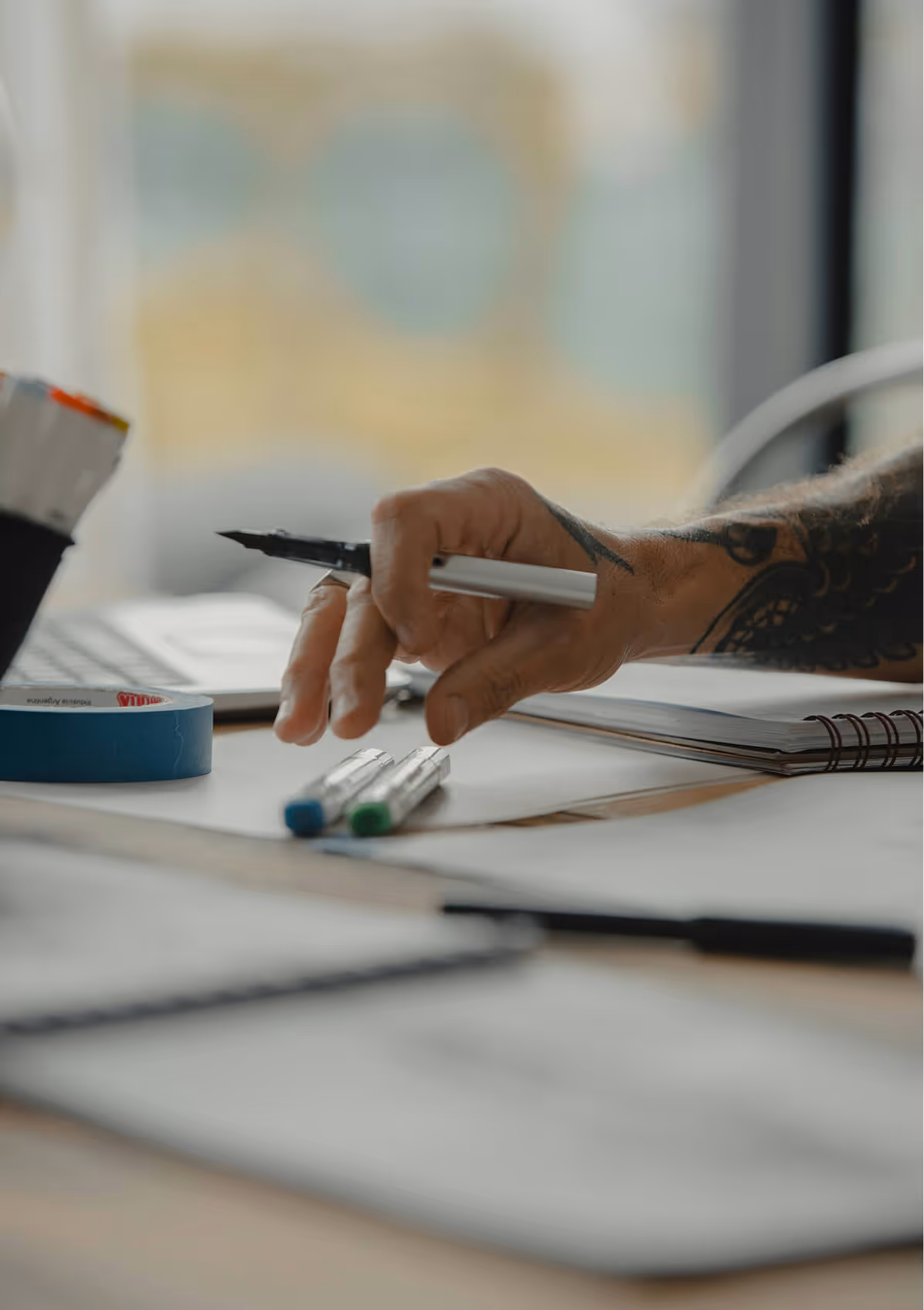 A hand holding a pencil and hovering over some paperwork.