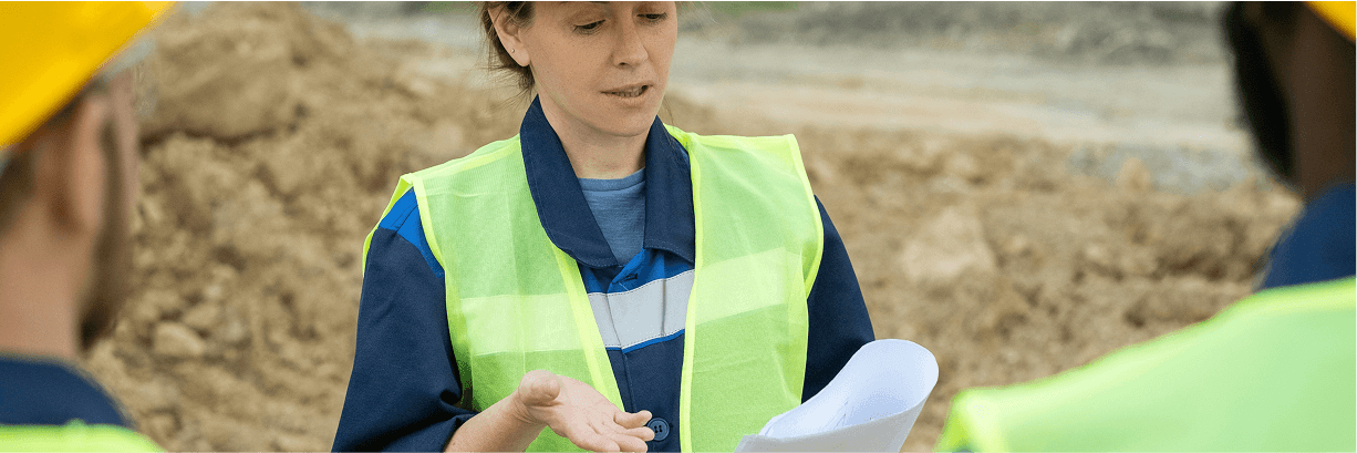 Drei Personen in Gespräch auf einer Baustelle.