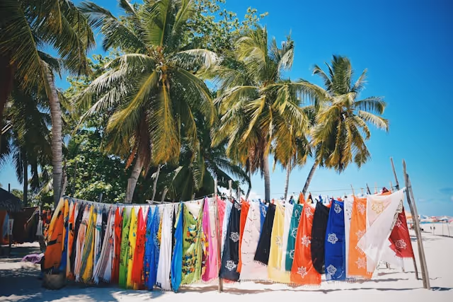 Colourful beach towels spread on a line on a beach.
