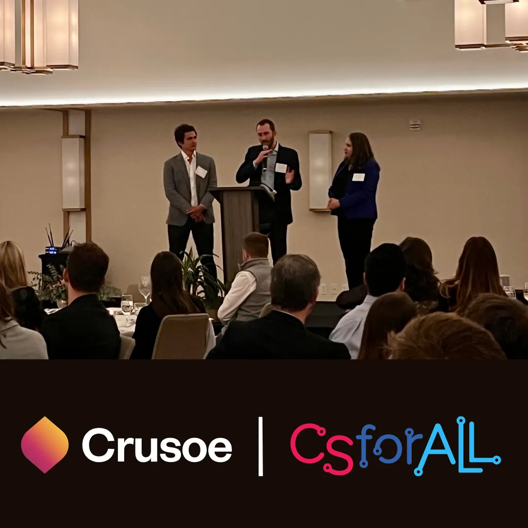 Photo of Crusoe founders speaking at a CSforALL community program presentation with an audience seated.