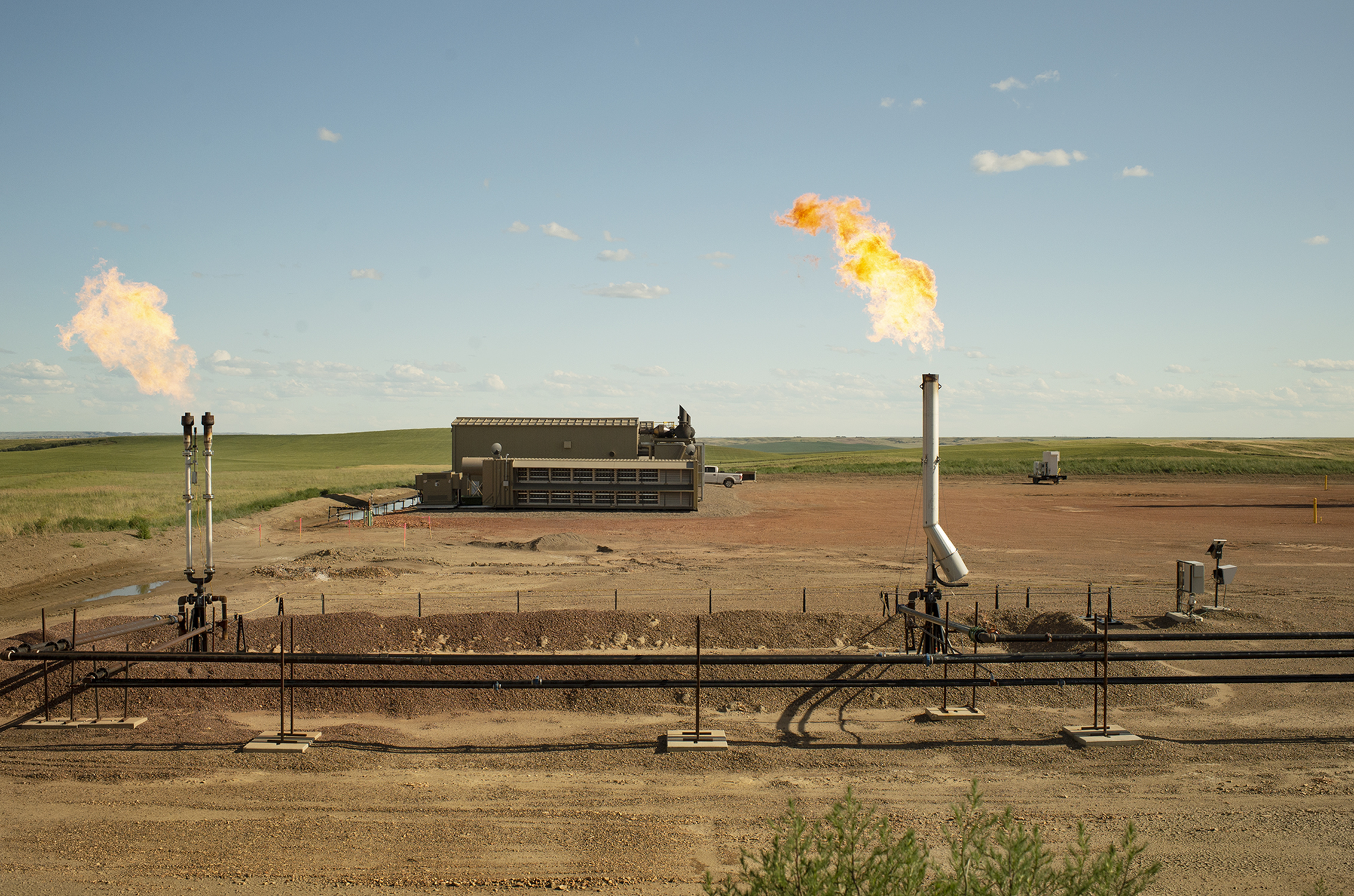 A Digital Flare Mitigation site operating in a rural landscape with two active flare stacks burning excess natural gas.