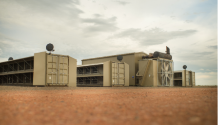 A low-angle, tilt-shift style photograph of a modular data center facility in a remote location.