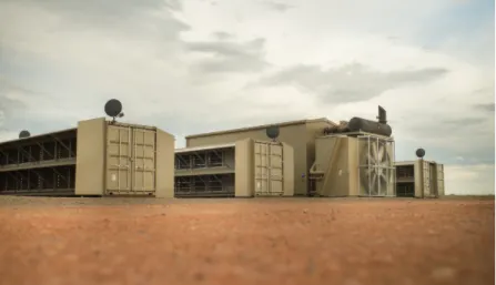 A low-angle, tilt-shift style photograph of a modular data center facility in a remote location.