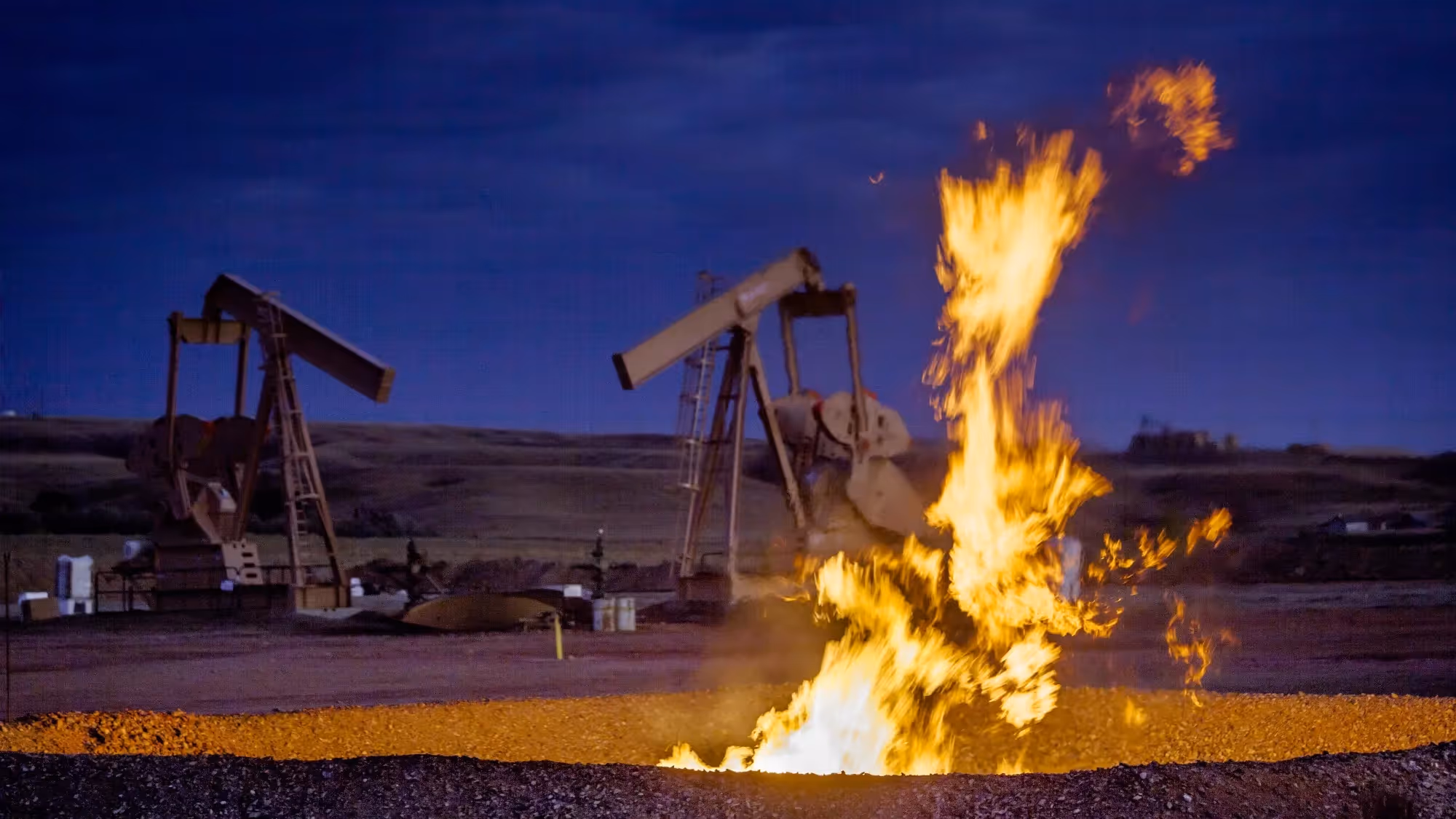 Photo of oil field flare gas burning at night.