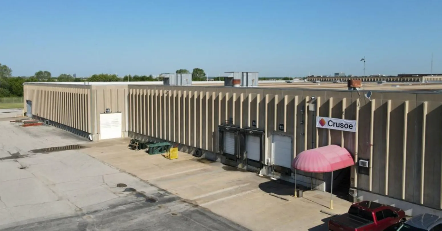 Exterior view of a Crusoe data center, a large industrial building with a prominent Crusoe sign.