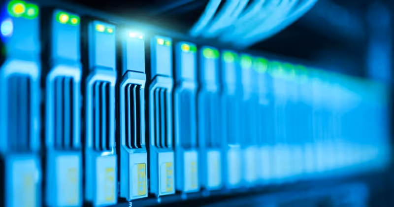 Close-up image of server components in a data center showing multiple storage drives with illuminated indicators.