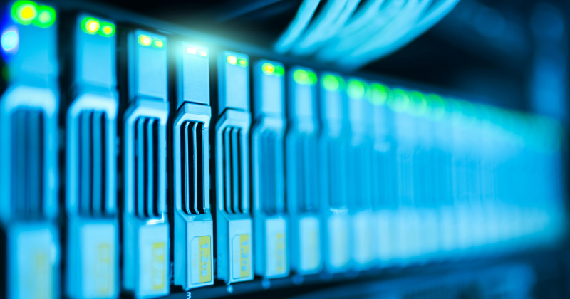 Close-up image of server components in a data center showing multiple storage drives with illuminated indicators.