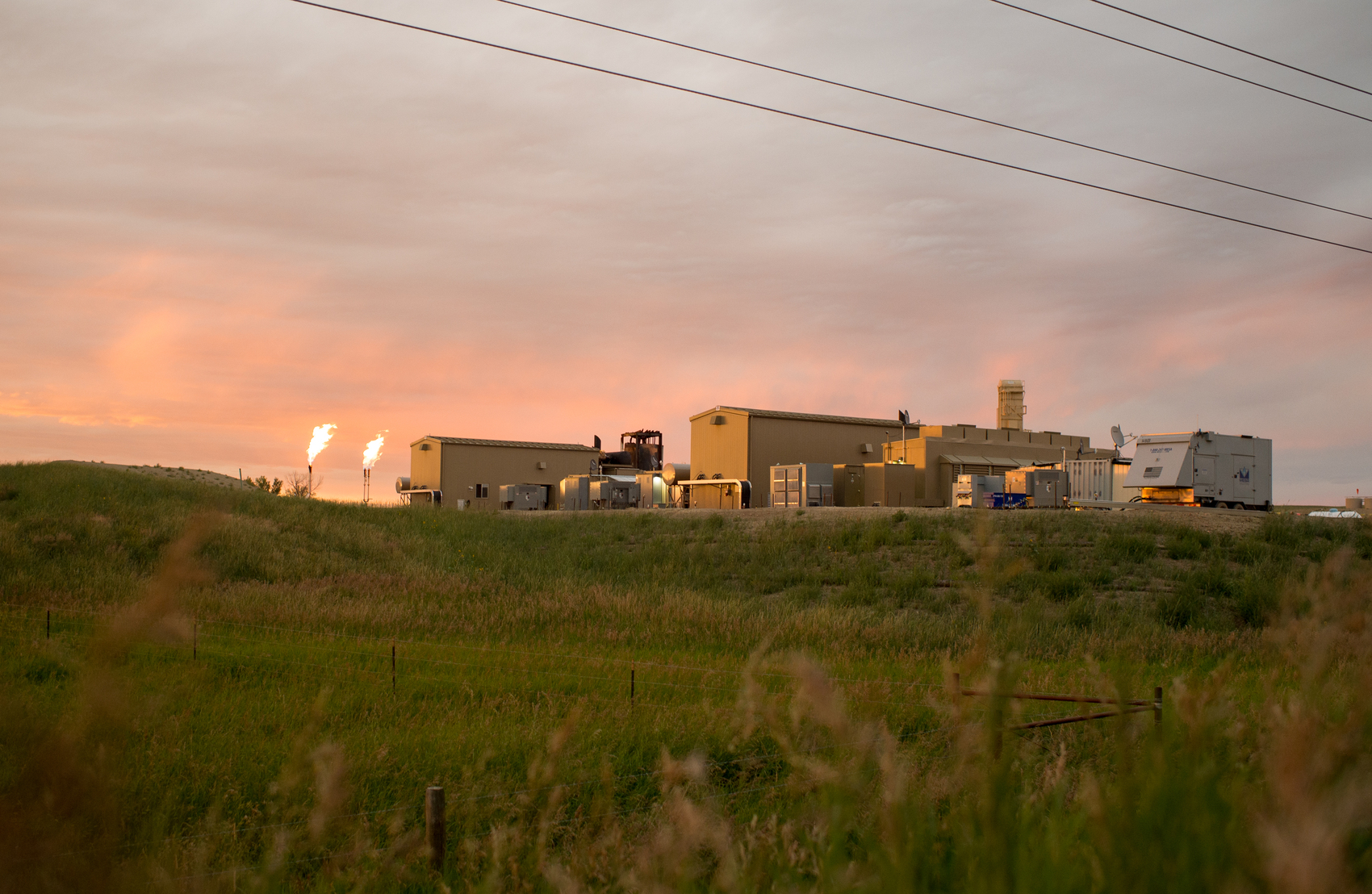 A Digital Flare Mitigation facility operating in a rural, grassy landscape at sunset.