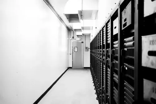 A black and white view down a long, narrow corridor in a data center.