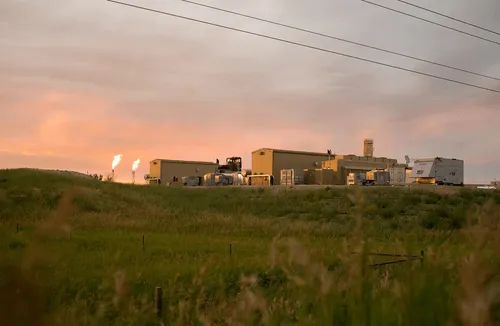 A Digital Flare Mitigation facility operating in a rural, grassy landscape at sunset.