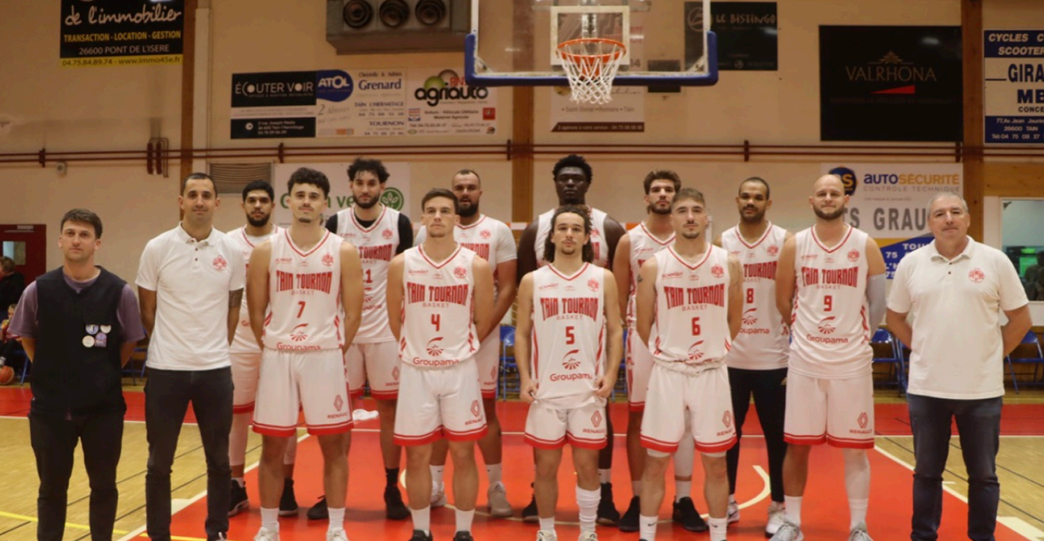 Équipe de basketball posant sur le terrain sous un panier dans un gymnase intérieur.