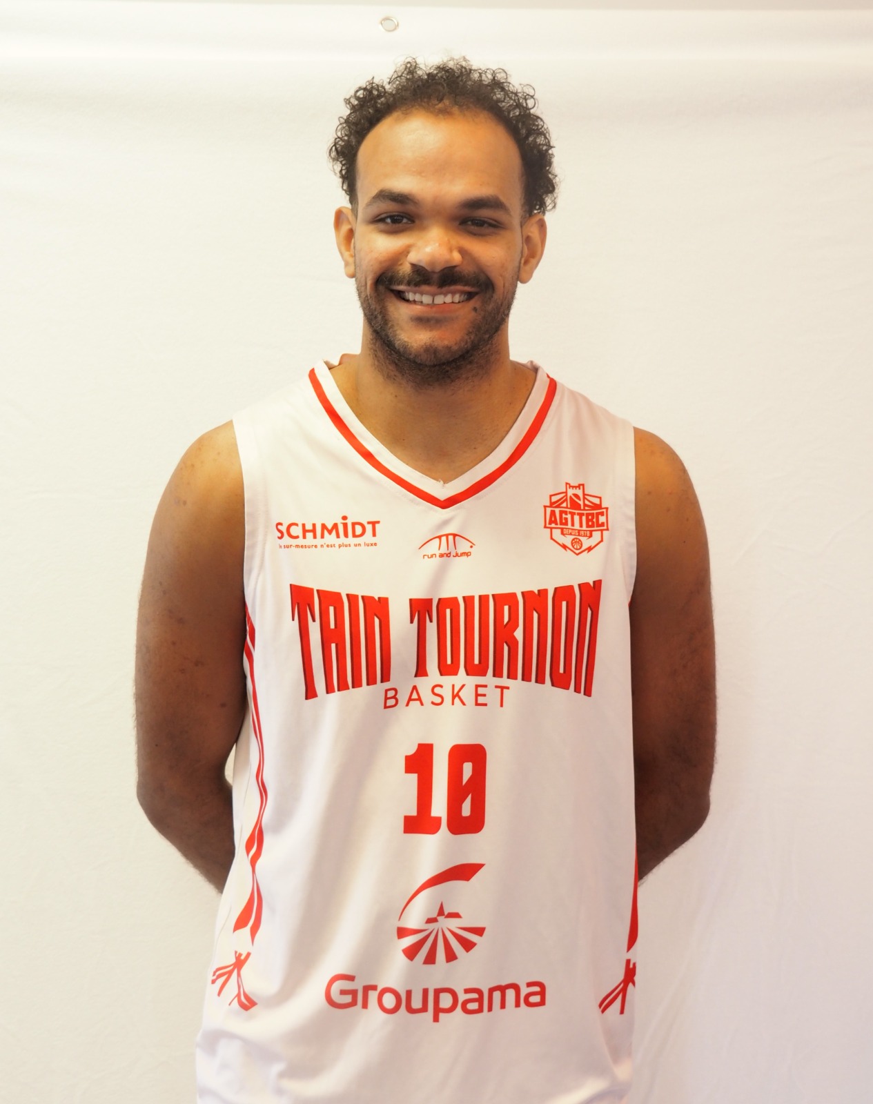 Joueur de basket souriant portant un maillot blanc Tain Tournon Basket numéro 10.