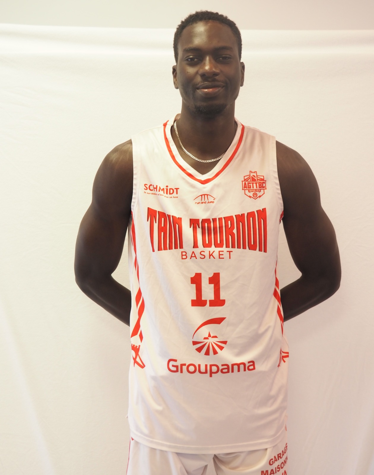Joueur de basketball portant un maillot blanc et rouge numéro 11 de l'équipe Train Tournon Basket.