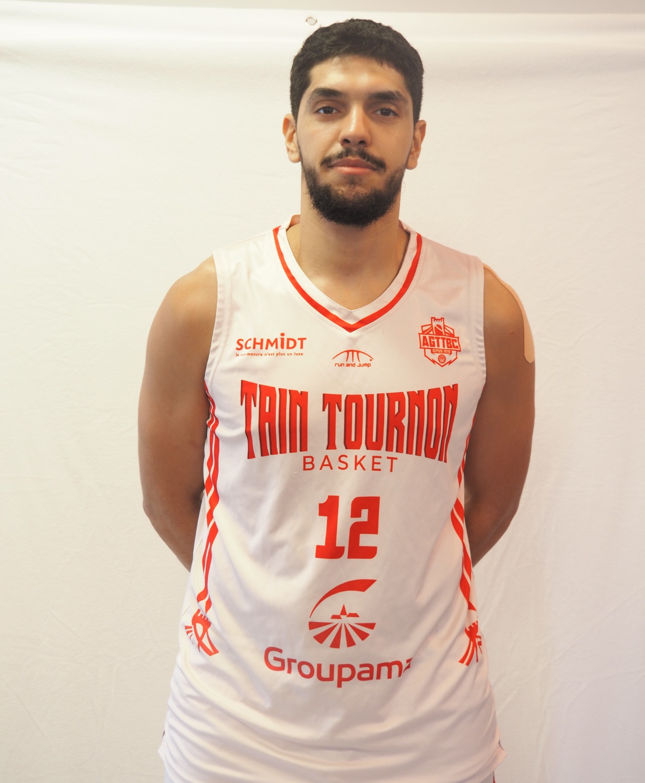 Joueur de basket portant un maillot blanc et rouge du club Tain Tournon numéro 12.