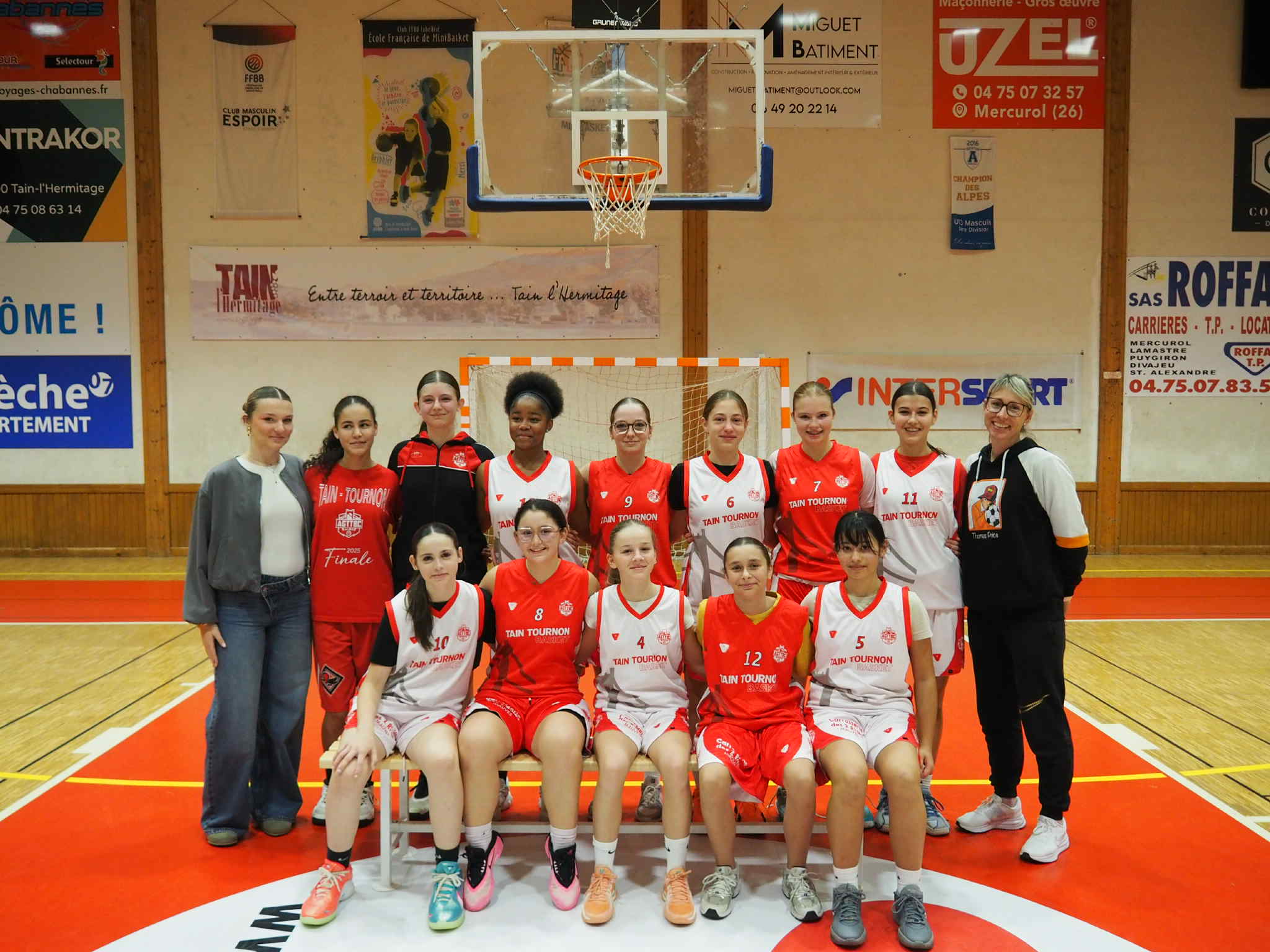 Équipe féminine de basketball posant ensemble sur un terrain de basket intérieur.