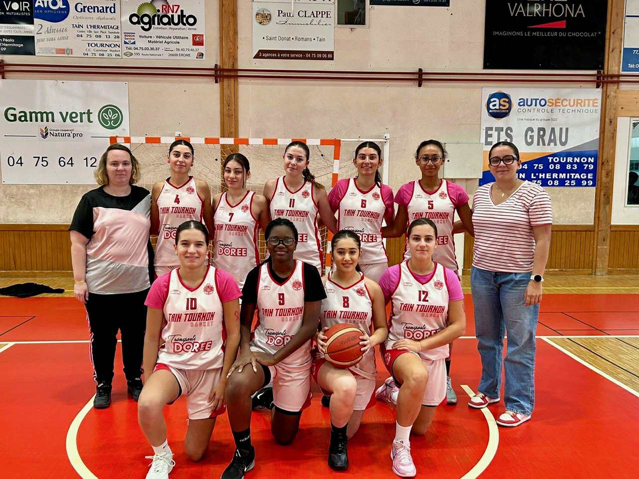 Équipe féminine de basketball du Tain Tournon posant sur un terrain intérieur.