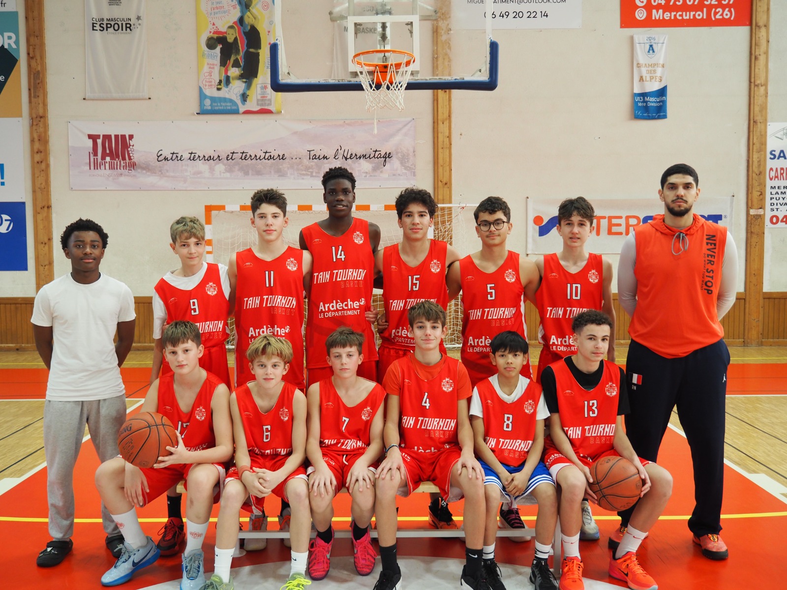 Équipe de basket-ball composée de jeunes joueurs en maillots rouges sur un terrain intérieur.