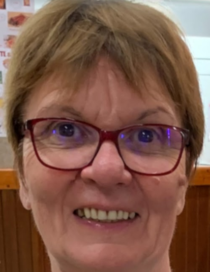 Portrait d'une femme souriante portant des lunettes rouges et ayant les cheveux courts clairs.