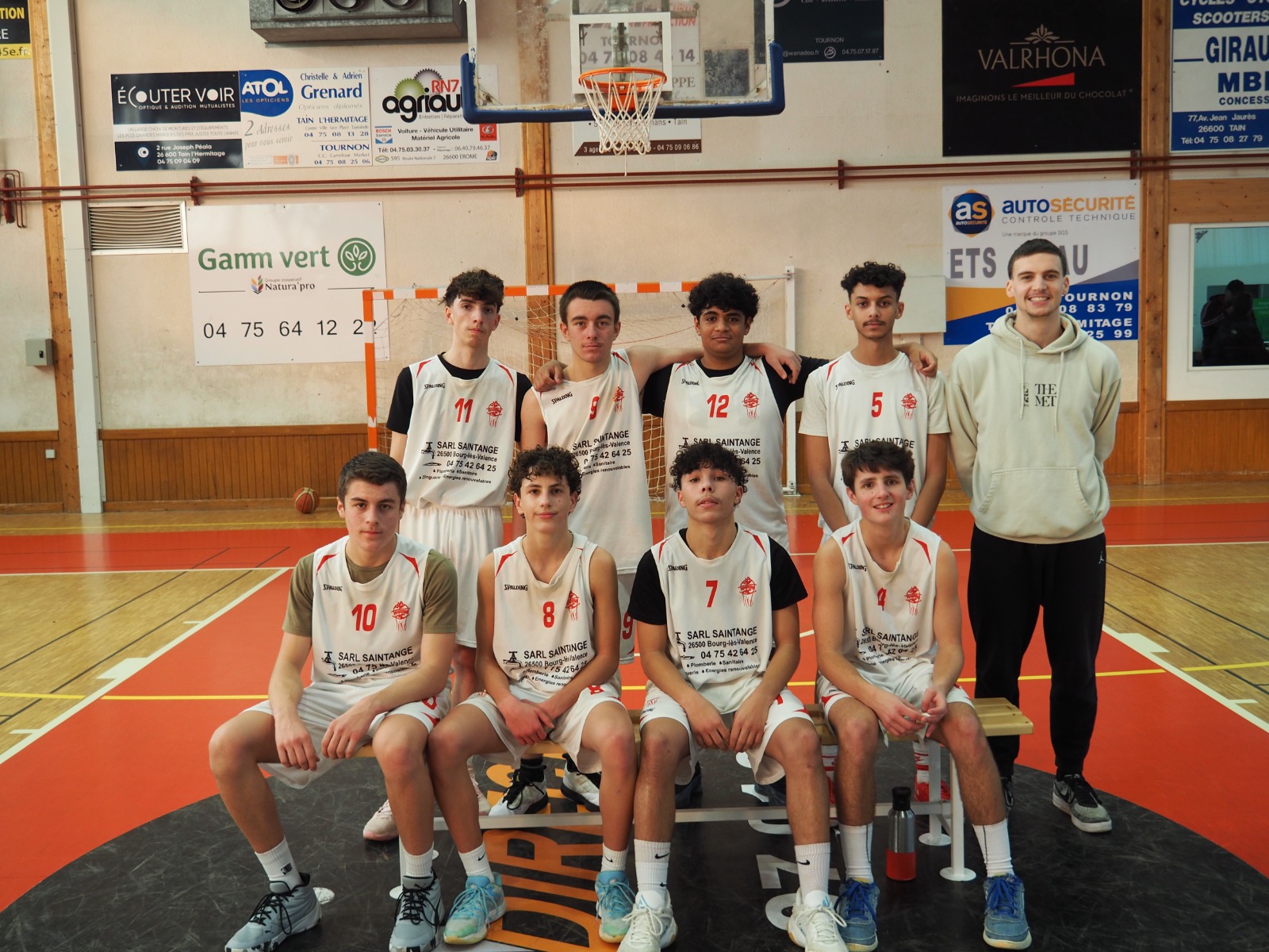 Équipe de basket-ball masculine posant sur un terrain intérieur devant un but de handball.