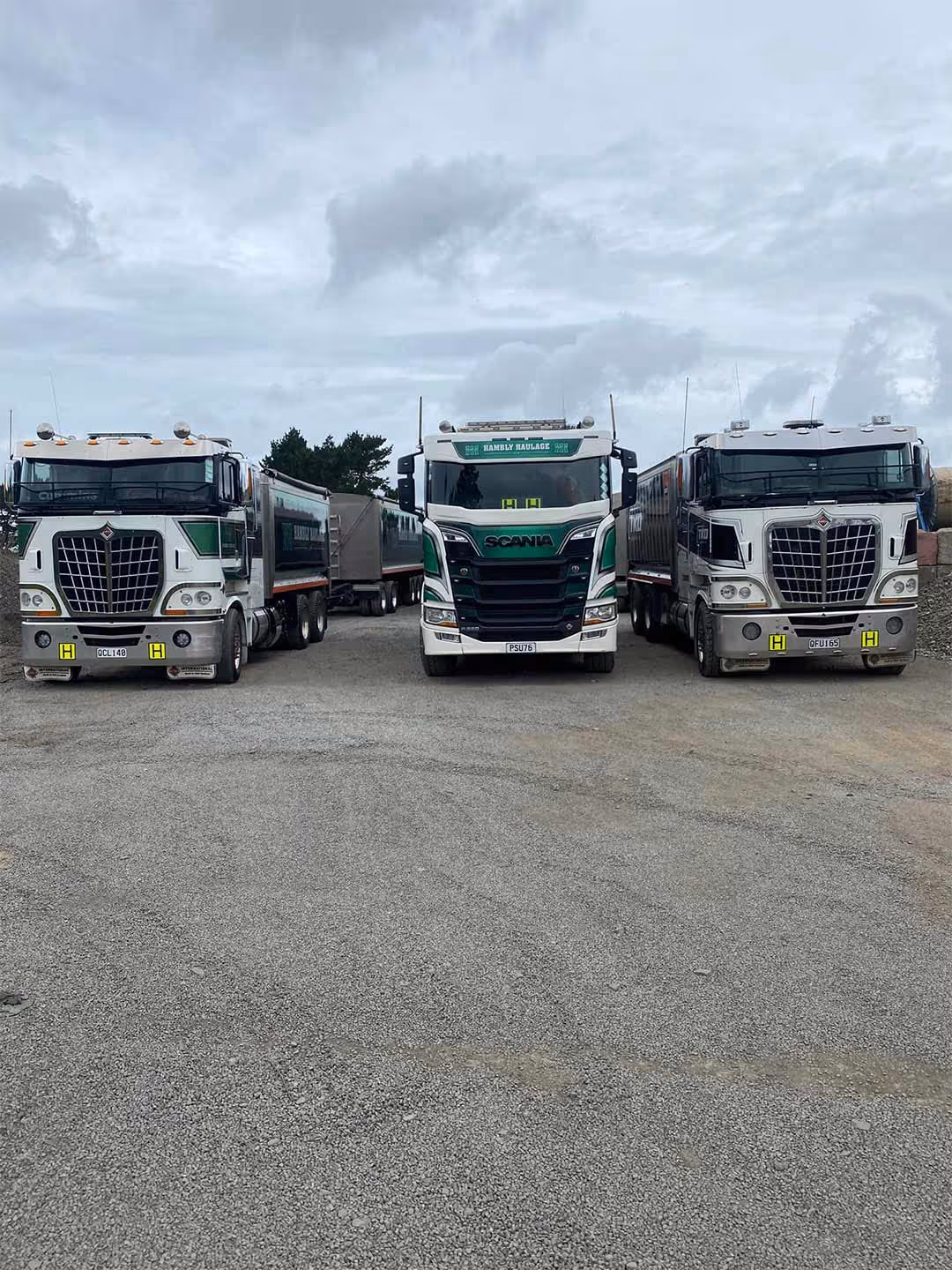 Trucks parked on gravel lot, green and white, ready for work outdoors freely.
