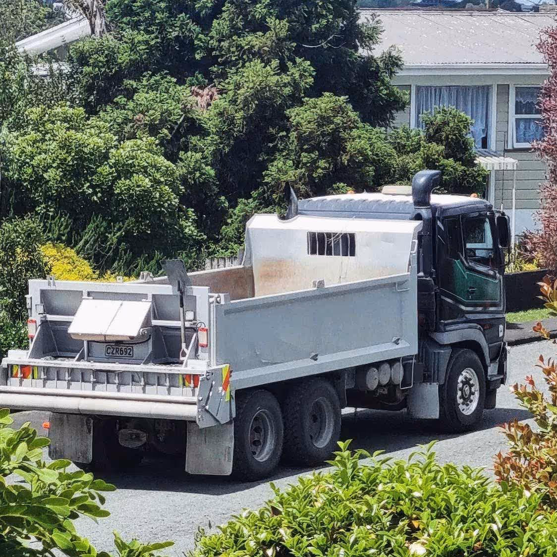 White cement mixer transported on a truck down a quiet residential street home.