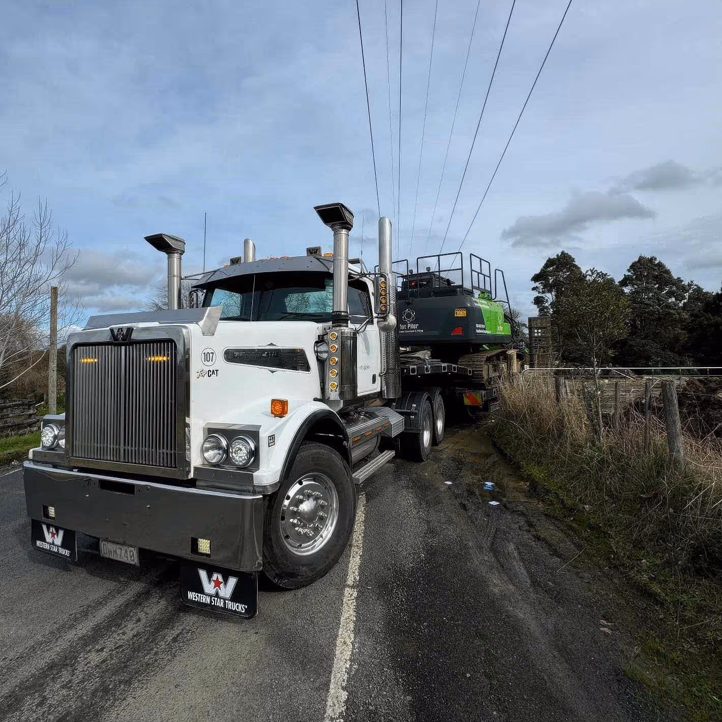 Western Star truck hauling Tat Piller load on a scenic rural American highway.