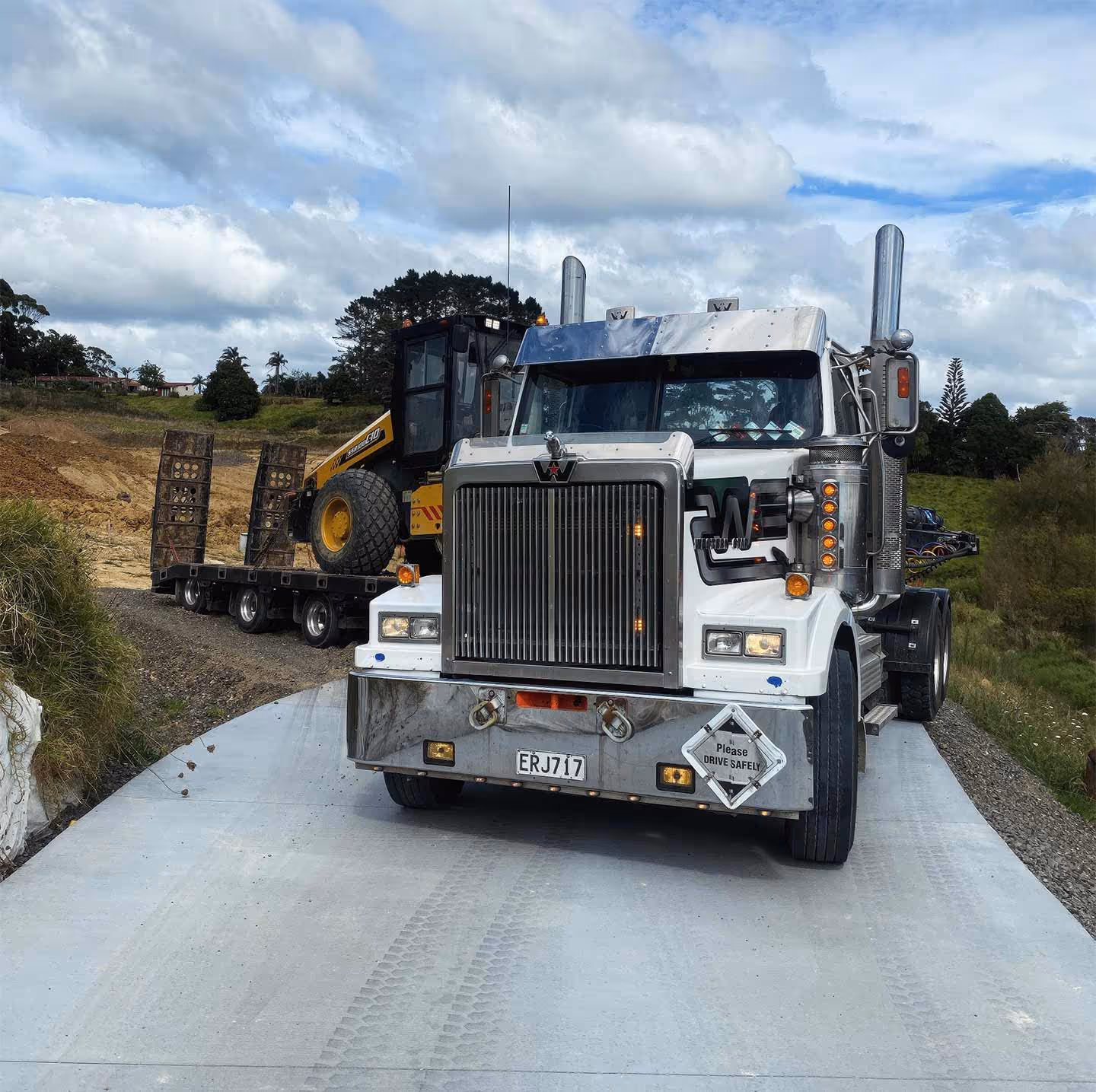 Construction trucks hauling yellow equipment on trailers crossing over a bridge safely outdoors.