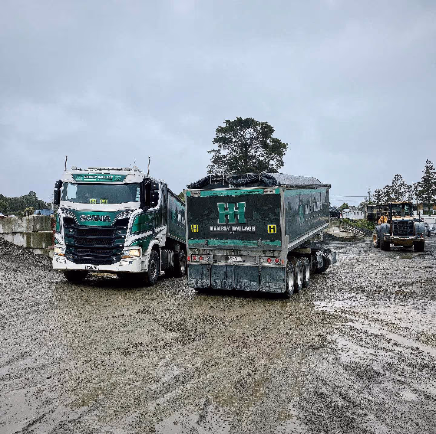 Heavy machinery transportation on dirt roads with Scania truck and trailer setup.