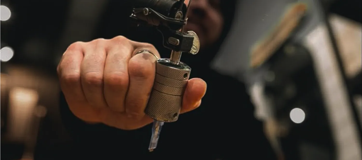 Tattoo machine held in a tattoo artist's hand, demonstrating the precision and control during the tattooing process.