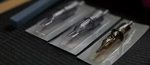 Various tattoo needles and cartridges neatly arranged, showcasing different sizes and types used by tattoo artists.