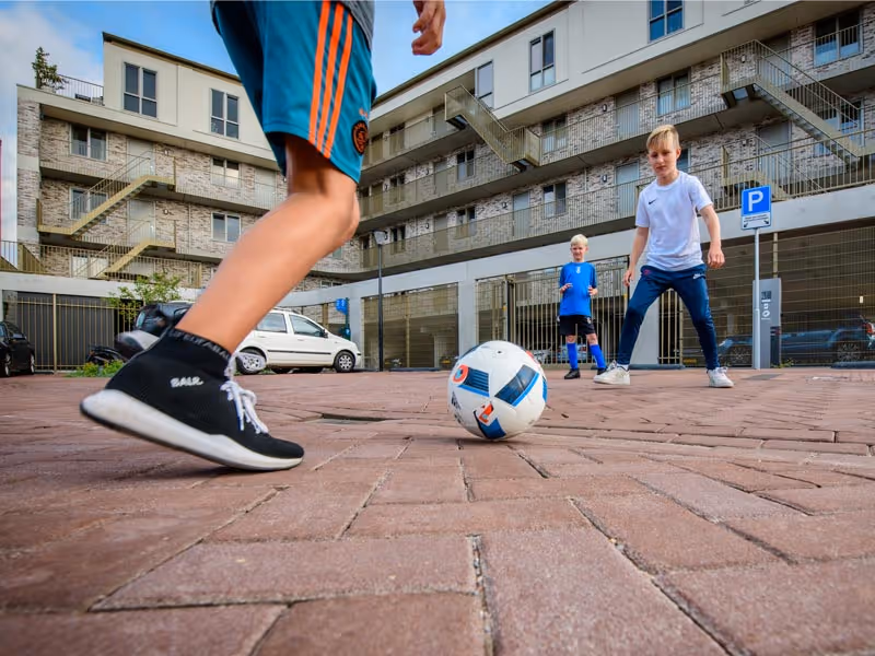 Kinderen spelen voetbal in wijk