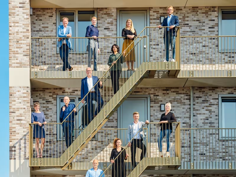 Teamfoto van DID op trap gebouw