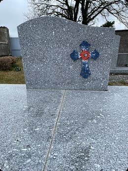 Croix en mosaïque colorée apposée sur une pierre tombale