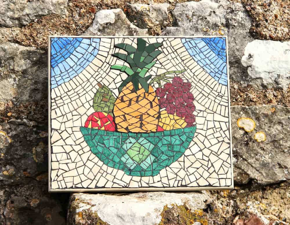 Mosaïque colorée représentant une coupe de fruits avec différents motifs décoratifs