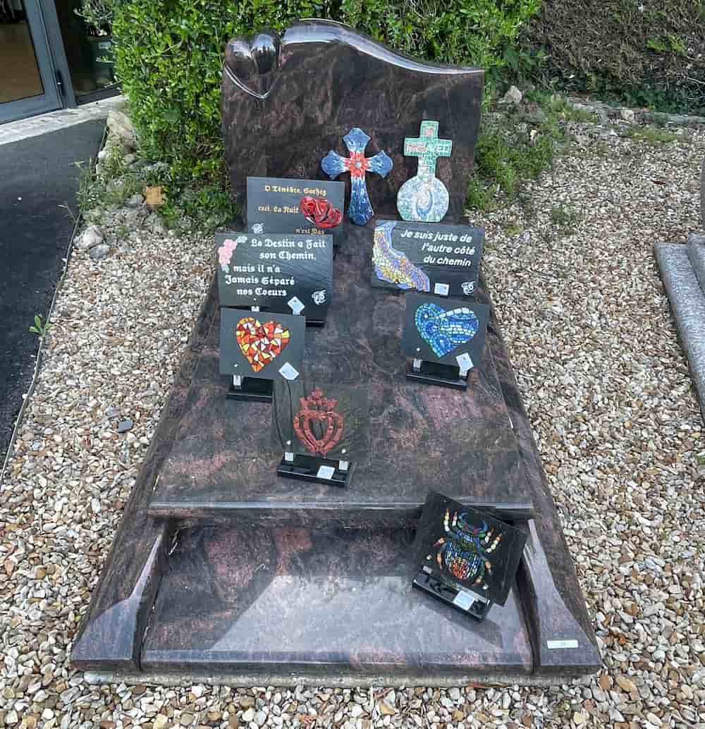 Tombe décorée de plusieurs plaques commémoratives et de croix en mosaïque colorée